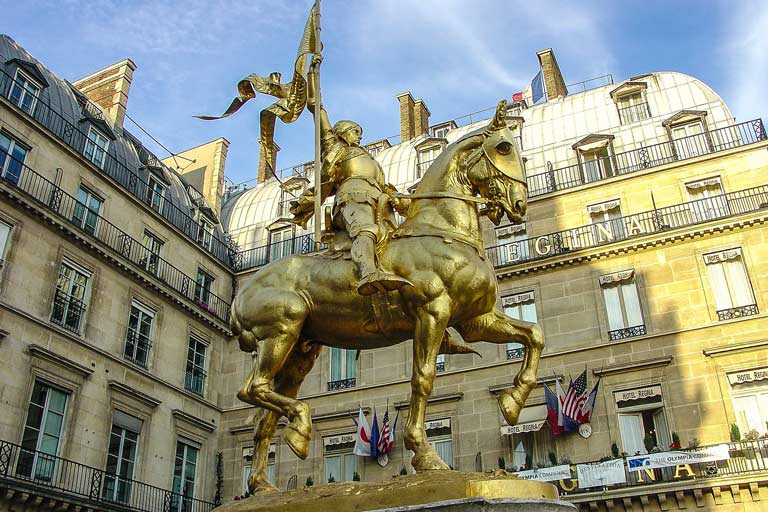 gold statue of Joan of Arch on a horse raising a flag